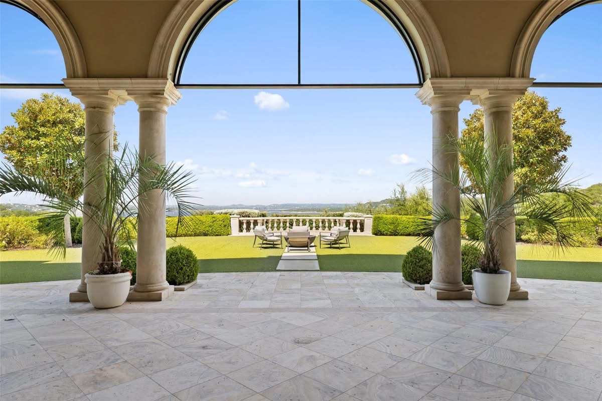 Arched terrace with columns overlooking a lawn and hillside view